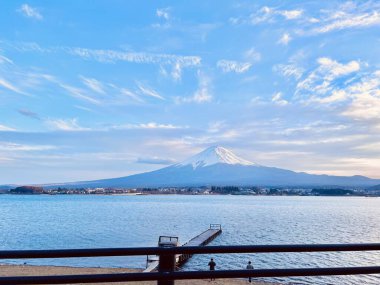 Akşam manzarası. Fuji ve göl. Çitin arkasından bak. Karla kaplı dağ. Fuji, mavi gökyüzü ve Lakeside, Japonya 'da bir rıhtım, popüler bir dönüm noktası ve turistik bir yer..