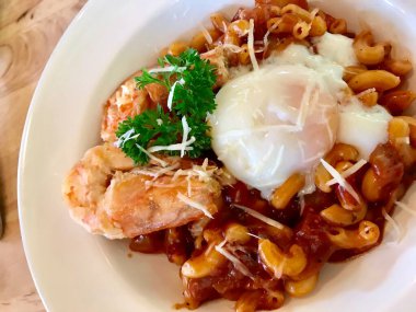 Karidesli makarna gibi, peynirli ve domates soslu. Üzerine rafadan yumurta ve garnitürle süslenmiş. Resmi kapat..