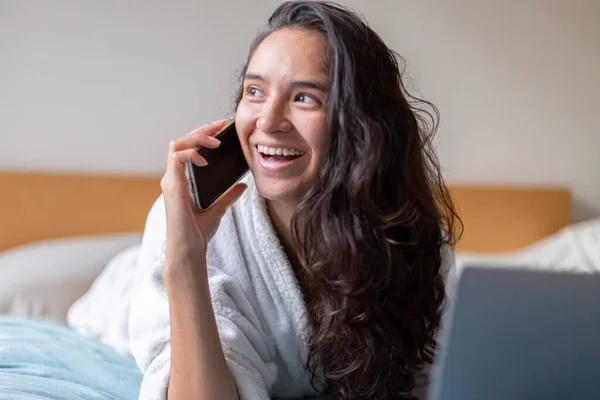 Happy woman speaking with cellphone in bedroom at home