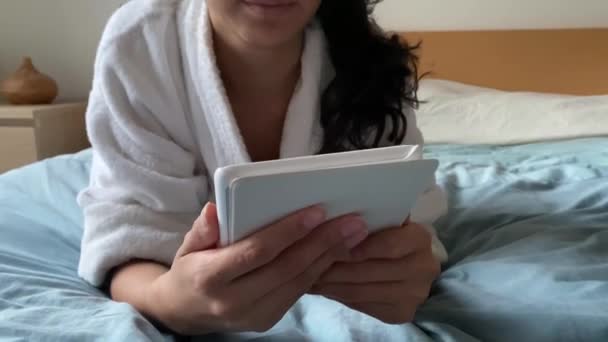 Jonge Vrouw Badjas Het Lezen Van Een Ebook Bed — Stockvideo