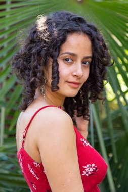 Kıvırcık saçlı genç bir kadın cennette eğleniyor. 