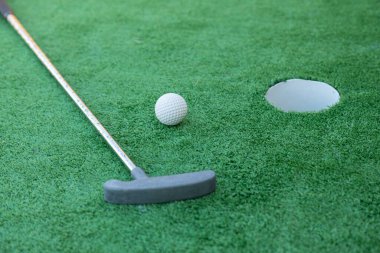 Mini golf equipment, golf club, ball and hole on green ground 