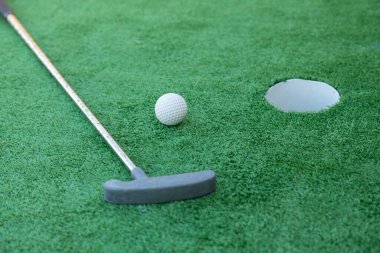 Mini golf equipment, golf club, ball and hole on green ground  clipart