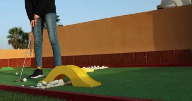 Tanımlanamayan bir kadının mini golfte golf sopasıyla topa vuruşunun yakın çekimi. 