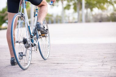 Güzel şehir parkında bisiklet hazırlayan spor giyimli genç, havalı erkek bisikletçinin arka görüntüsü.