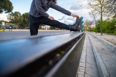 Spor kıyafetli, spor paten giyen, parktaki bankta gerinen genç, havalı bir adam.