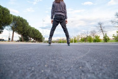 Spor giyimli, kimliği belirsiz, genç ve havalı bir erkek paten sürerken parkta çok hızlı yol alır.