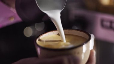 Bir kafede kahveye süt dökmeye yakın çekim. Profesyonel barmen kahve dükkanında cappuccino hazırlar. Yüksek kalite 4k görüntü