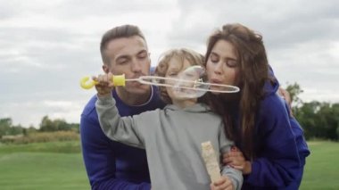 Kafkas ailesi birlikte sabun köpüğü üflüyor. Doğada eğlence, ebeveynler ve oğullar birlikte oynarlar ve eğlenirler. Ebeveyn sevgisi kavramı. Yüksek kalite 4k görüntü