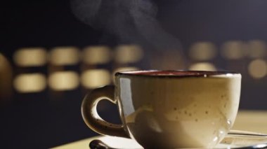 Dumanı tüten bir kahvenin yavaş çekimini yakın çekim. Bir kafedeki masanın üzerinde bir cappuccino duruyor ve içinden buhar çıkıyor. Yüksek kalite 4k görüntü