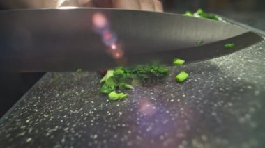 Kesme tahtasındaki yeşil soğanları dilimlerken çekilmiş yavaş çekim videosu. Yüksek kalite 4k görüntü