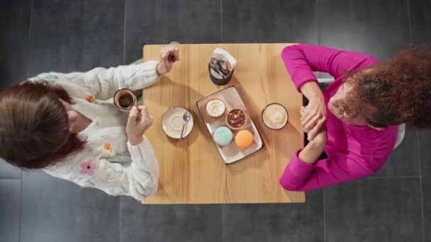 两个女孩在咖啡店喝咖啡 女性朋友快乐地相遇在一起 非洲裔美国妇女和白人女孩在咖啡店 高质量的4K镜头 — 图库视频影像