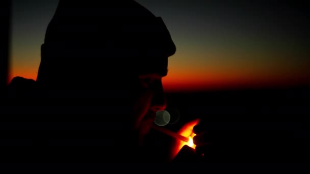 日没時にタバコを灯す男のスローモーションビデオ タバコを吸って煙を吹いている男のシルエット 高品質4K映像 — ストック動画