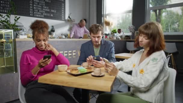 Tre Vänner Från Flera Raser Använder Telefoner Ett Kafé Sociala — Stockvideo