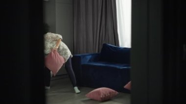Yaşam tarzı anne, oğluyla evde yastıklarla kavga ederek eğleniyor. Eğlence, neşe, mutluluk, ev konforu ve bir kadının çocuk sevgisi. Yüksek kalite 4k görüntü