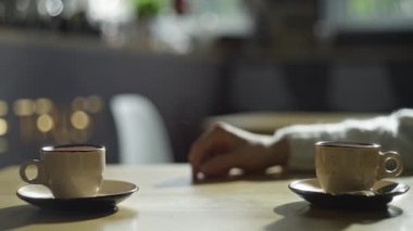 Kafede buluşan mutlu genç bir çift. Bir erkek, bir kafede bir kadının elini nazikçe ve romantik bir şekilde okşar. Sevgililer buluşması, kahve için. Yüksek kalite 4k görüntü