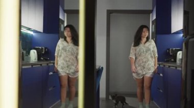 Yaşam tarzı kadın yatak odasından mutfağa gelir ve telefonu ve bir fincan kahveyi alır. Kız evde haberleri ve sosyal ağları okuyor. Yüksek kalite 4k görüntü
