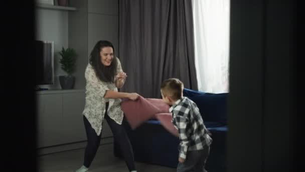快乐的母亲和儿子在客厅里抱着枕头鬼混 一家人在家里玩得很开心 高质量的4K镜头 — 图库视频影像