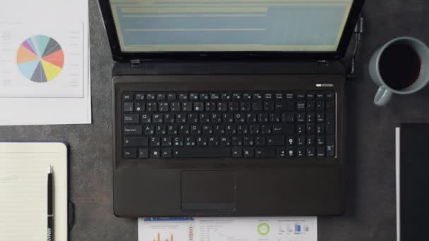 一个工作月的特写在一个男性的办公室里 手里拿着一张印有图表的纸 一台笔记本电脑和一杯咖啡 商人研究工作文件 高质量的4K镜头 — 图库视频影像