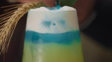 Mavi ve sarı karışımlı hazır Ukrayna kokteylinin yakın çekimi. Güzel bir alkollü içecek. Yüksek kalite 4k görüntü