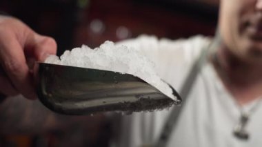 Slow motion close-up video of a bartender pouring ice into a glass. Preparation of cold cocktails for a party at the restaurant bar. High quality 4k footage