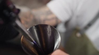 Close-up of a bartender pouring alcohol into a jigger at the bar. Preparation of alcoholic beverages for a party in a club. High quality 4k footage
