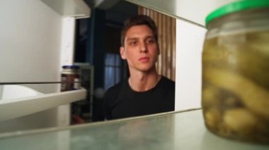The man opens the refrigerator in search of food, but it is empty. Home life and cooking. Close-up of a disgruntled guy looking at whats in the fridge. High quality 4k footage
