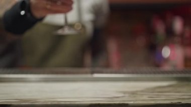 Close-up of the bartender placing a glass with a cocktail on the bar. Fun party in the club and alcoholic drinks. High quality 4k footage