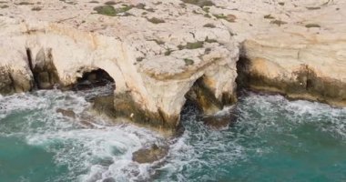Aerial view of the landscape of waves crashing on the rocks. A beautiful ocean whose waves crash against reefs and stones on the shore in slow motion. High quality 4k footage