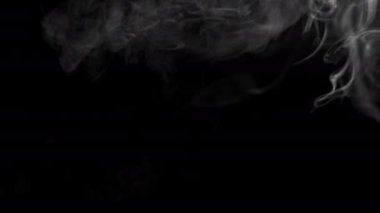 Abstract video of billowing smoke from a fire. How clouds float and form. Strong puffs of smoke on a black background. High quality 4k footage