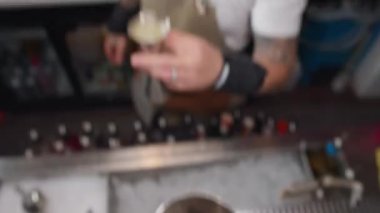 Slow motion video of pouring alcohol to mix a cocktail into a shaker. A professional bartender works at a bar in a restaurant. High quality 4k footage