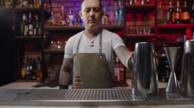 A charismatic bartender starts preparing a cocktail. the man takes the shake and tosses it. High quality 4k footage
