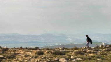 Dağlarda yürüyüş yapan bir kadının hava manzarası. Aktif eğlence, yalnız bir kız güzel bir manzarada bir dağ sırtı boyunca yürüyor. Yüksek kalite 4k görüntü