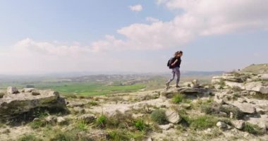 Aerial view Caucasian woman with a backpack climbs the mountains. Haikin in a beautiful landscape. Active recreation and outdoor sports. High quality 4k footage