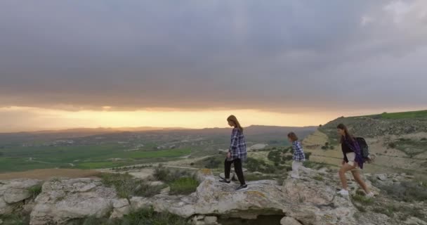 家族は山の中で一緒にハイキングしています 2人の娘と山の範囲の石の上にエキサイティングな自然と母 自由と自然との一体性の生活 — ストック動画