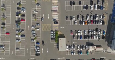 Aerial view of the cityscape of the parking lot near the mall. Cars are parked in the parking lot in a line leaving and arriving at the supermarket for purchases. High quality 4k footage
