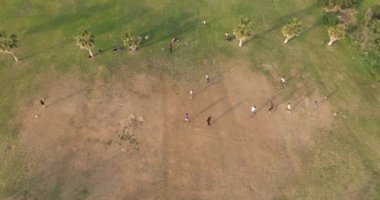 Çimlerin üzerinde futbol oynayan çocukların hava görüntüsü. Uykulu oğlanlar ve kızlar parkta topla koşuşturuyorlar. Yüksek kalite 4k görüntü