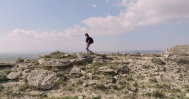 Sırt çantalı bir kadının dağlarda yürüyüşünün havadan görüntüsü. Kız dağlardaki kayalara tırmanıyor. Yüksek kalite 4k görüntü
