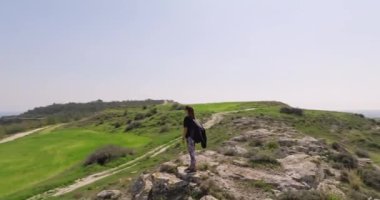 Aerial view of a sporty woman with a backpack standing on a rock in the mountains. The concept of happiness, satisfaction and freedom, victory. High quality 4k footage