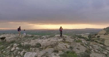 Aerial view mother and daughters walking on stones and rocks in the mountains. The family actively spends time together hiking. High quality 4k footage