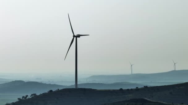 山の中で回転する風車ブレードとタービンの壮大なビデオを空中からご覧ください 緑のエネルギー 生態系と代替風力エネルギー 高品質4K映像 — ストック動画