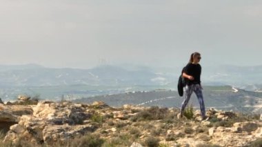 Sırt çantalı, dağlarda taş ve kayaların üzerinde yürüyen bir kadının havadan görünüşü. Doğada özgürlüğü hisseden güzel bir kız. Aktif eğlence yürüyüşü. Yüksek kalite 4k görüntü