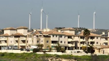 Arka planda rüzgâr tarlası olan şehir manzarası. Temiz ekolojik rüzgar elektriği üretimi. Geleceğin evi. Yüksek kalite 4k görüntü