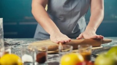 Yorgun bir kadın hamur işini hazırlarken hamuru yuvarlar. Bir kız için mutfakta çalışmak çok zor. Ekmek ve kek pişiriyorum. Yüksek kalite 4k görüntü