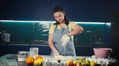 Bir kadın kek hamuru hazırlamak için süt kreması ekler. Ev yapımı tatlı hamur işlerinin hazırlanması ve pişirilmesi. Yüksek kalite 4k görüntü
