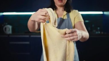 Bir kadın mutfakta pizza hamuru gerer. Kız evde hamur işi pişiriyor. Ev yapımı ekmek ve tatlı bir yaşam tarzı. Yüksek kalite 4k görüntü