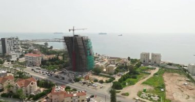 Deniz kıyısında daireleri olan yüksek katlı bir binanın havadan görünüşü. Okyanus kıyısındaki güzel bir şehir manzarasında, bir evin yanındaki musluk. Yüksek kalite 4k görüntü