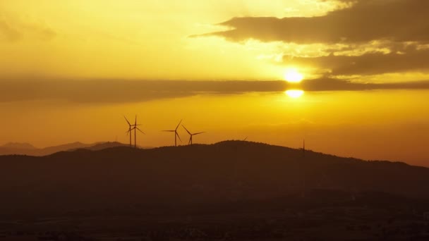 山の中で日没の風車の空中ビューシルエット 風力エネルギーを利用した代替エネルギーやエコ電力の生産です 高品質4K映像 — ストック動画
