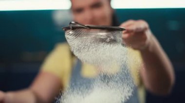 Un süzgeçten geçerken yavaş çekim videosu. Bir kadın evdeki mutfakta ekmek pişirmek için hamur hazırlıyor. Yüksek kalite 4k görüntü