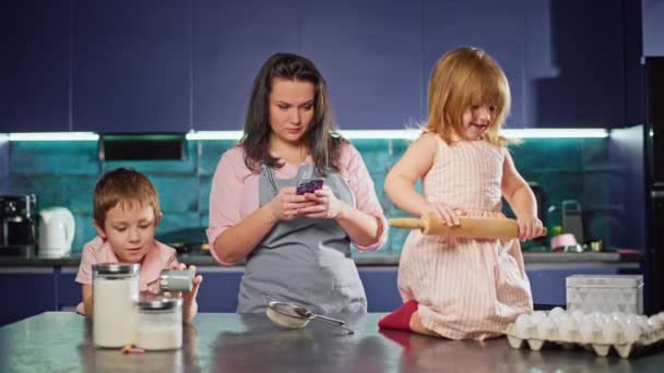 Mama Patrzy Przepis Jej Telefon Podczas Gdy Dzieci Bawią Się — Wideo stockowe